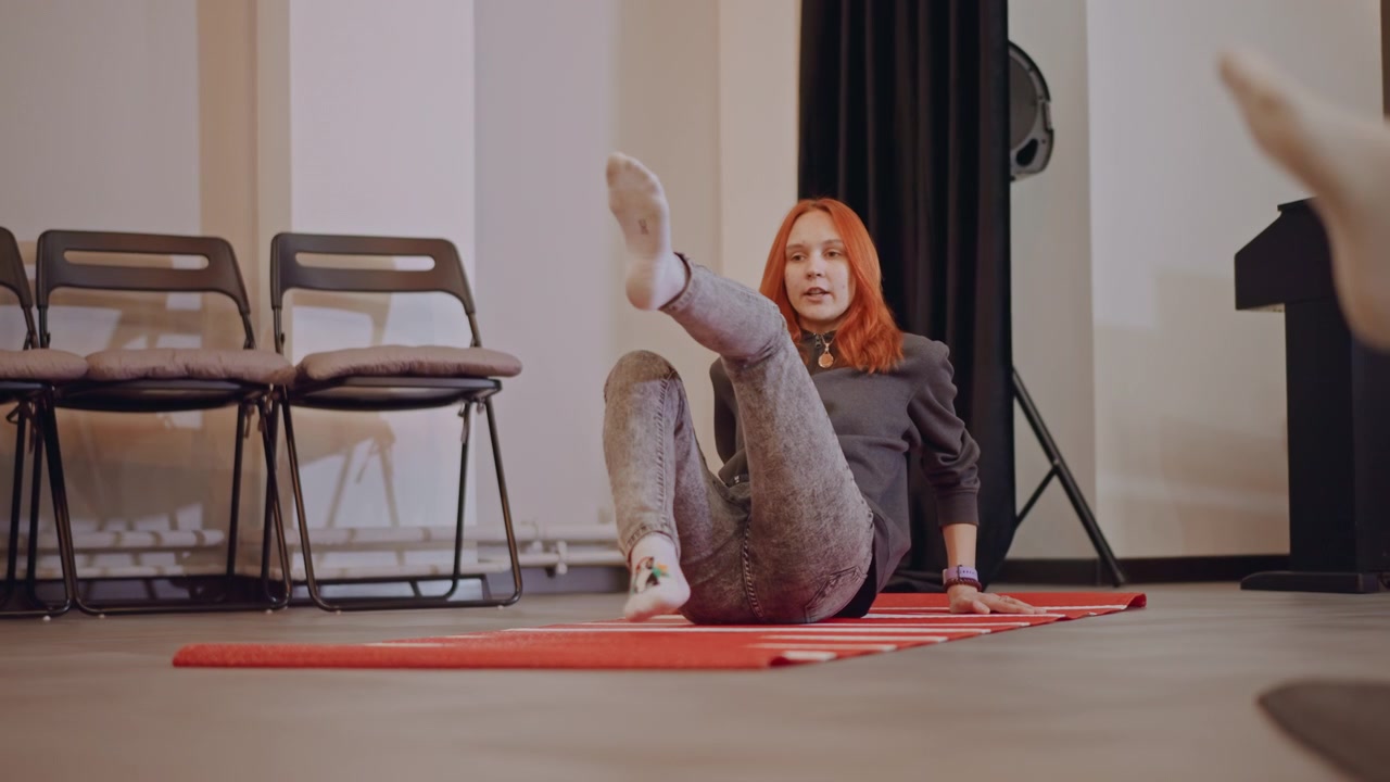 Redhaired woman practicing breathing indoors. Female with red hair doing breathing routines indoors. Woman with red hair performing breathing exercises in compact studio setting during warmup
