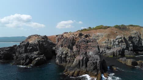 Toma-Aérea-De-Grandes-Rocas-En-El-Mar-Desde-La-Orilla-Del-Mar-En-Un-Día-Soleado-De-Verano