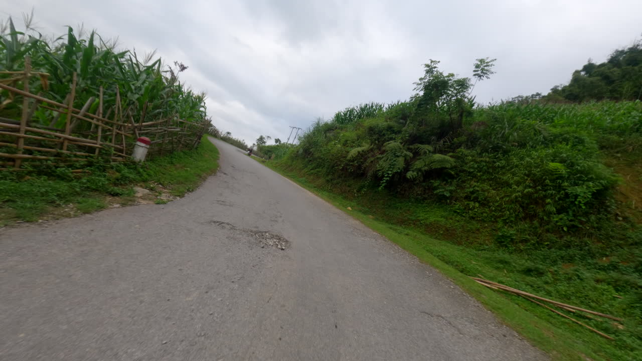 POV scooter journey through Ha Giang Loop, winding mountain roads and scenic vistas along grassy hills and farmland