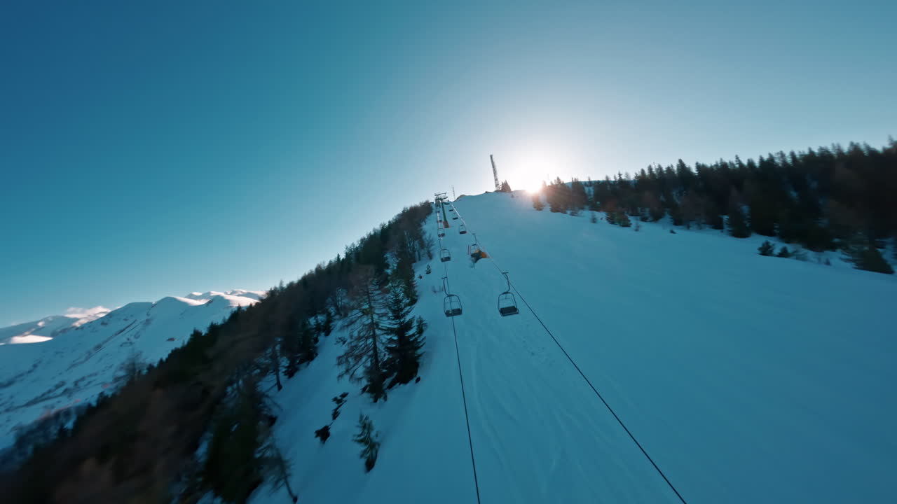 Aerial view of a snowy mountain with ski lift and trees at sunrise