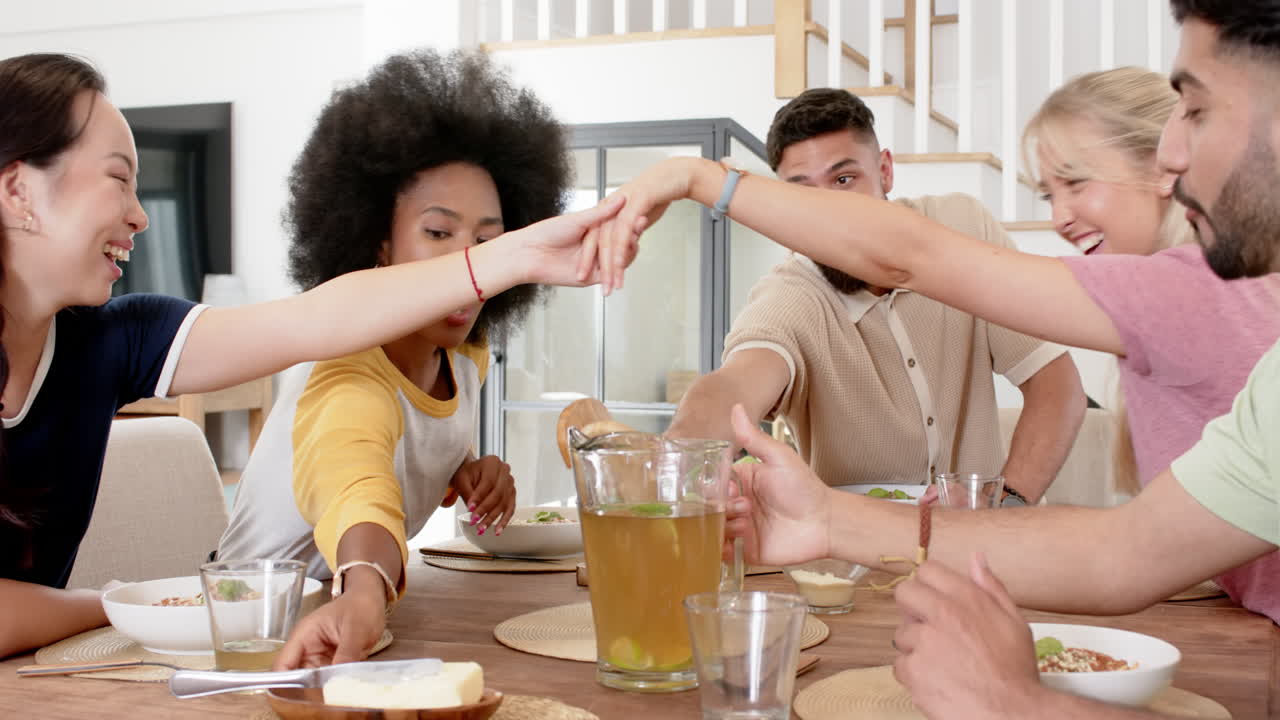 Friends enjoying meal together, raising glasses and sharing laughter at dining table