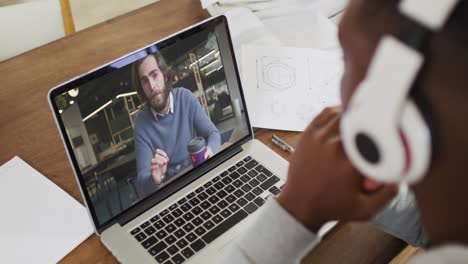 Afroamerikanischer-Männlicher-College-Student,-Der-Notizen-Hält,-Während-Er-Zu-Hause-Einen-Videoanruf-Auf-Dem-Laptop-Führt