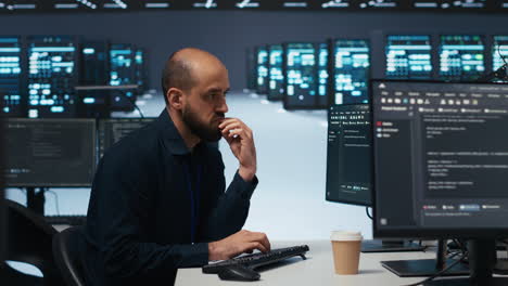 Engineer writing code in high tech facility with server rows