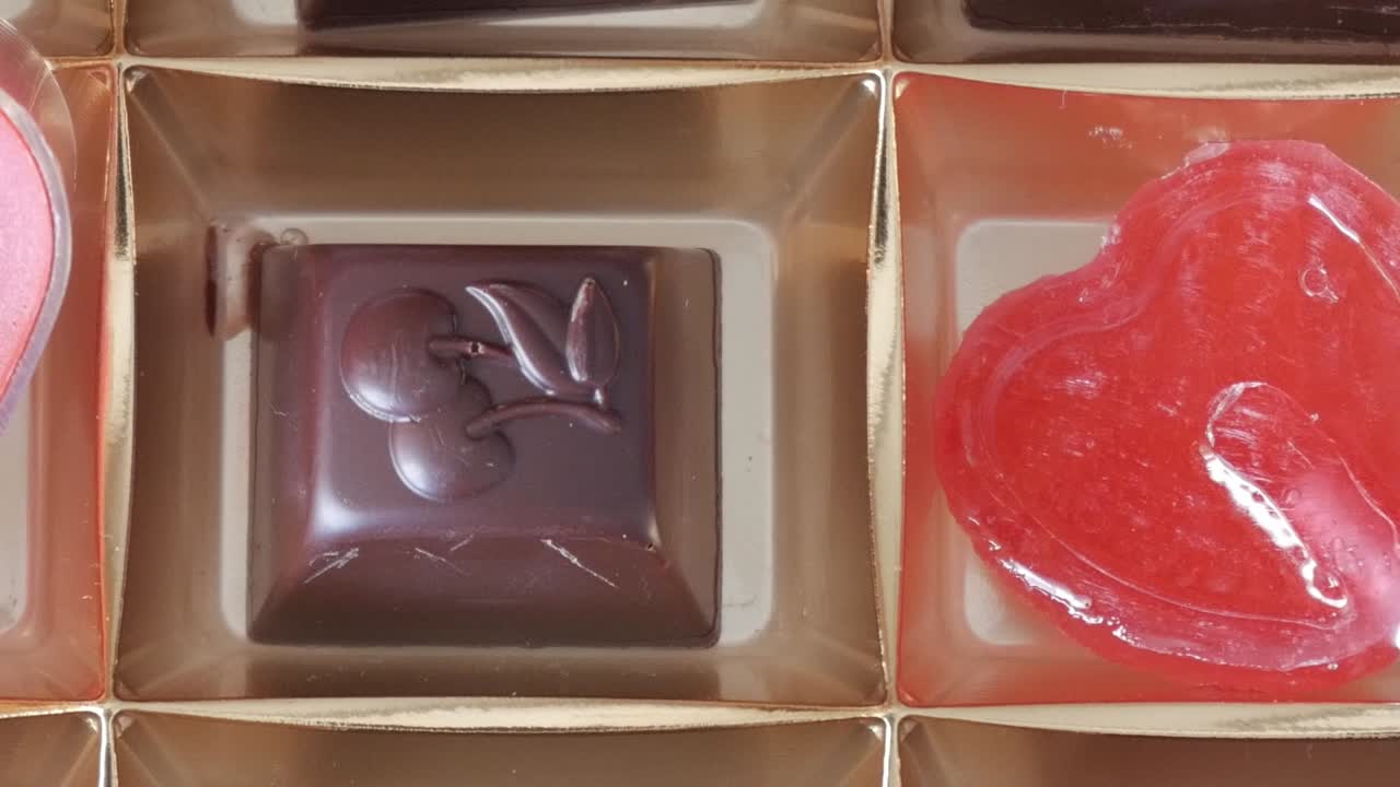 Heart-shaped lollipop being poured into chocolate molds for Valentine's Day treats