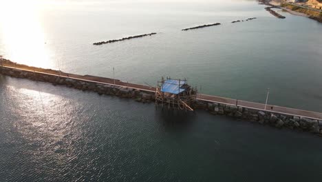 Aerial-landscape-view-of-a-trabucco,-traditional-fishing-machine,-on-the-italian-seashore,-at-dusk