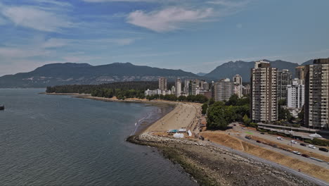 Vancouver-BC-Canada-Aerial-v117-flyover-English-Bay-capturing-views-of-sandy-beach,-Stanley-Park-and-West-End-and-downtown-cityscape-with-mountain-backdrop---Shot-with-Mavic-3-Pro-Cine---July-2023