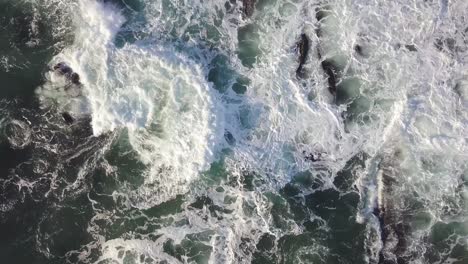 aerial view to ocean waves with the waves crashing on the rocks