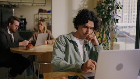 a young man working on his laptop in a coffee shop.