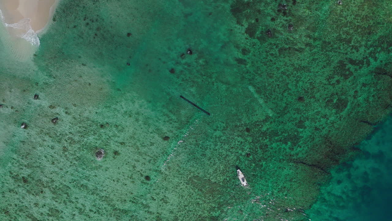 Overhead drone of shallow reef with waves and coral patterns in tropical ocean