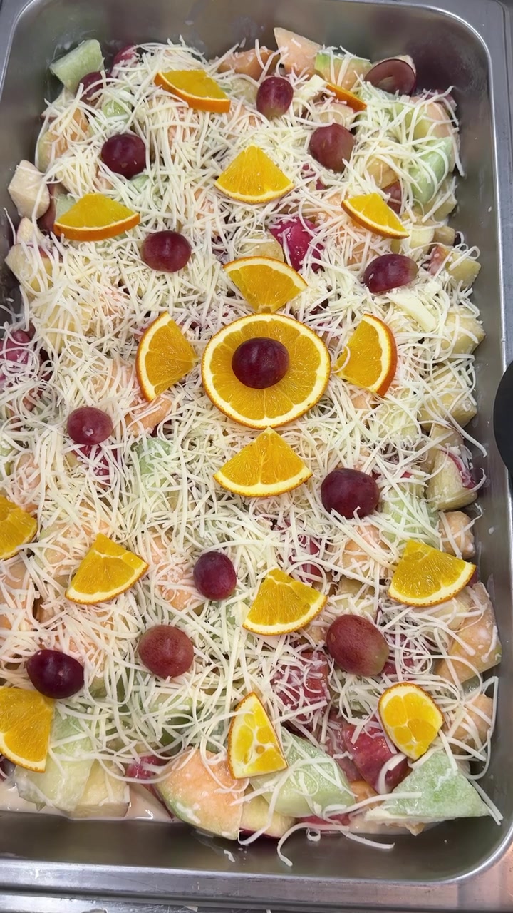 Macedonia di frutta colorata guarnita con formaggio grattugiato e guarnizione fresca