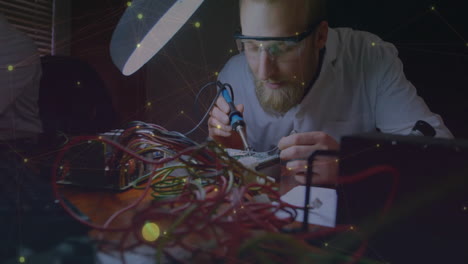 animation of communication network over caucasian male electrical engineer soldering at workbench