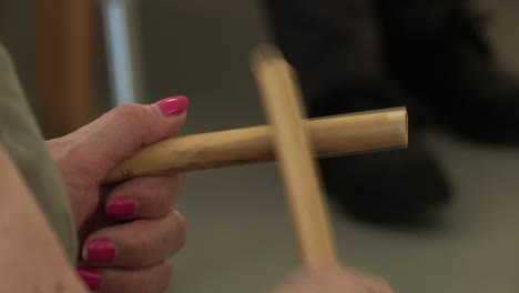 close-up of woman's hands with pink painted nails, playing bamboo sticks - music