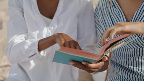 Nahaufnahme-Der-Hände,-Die-Am-Sommerstrand-Ein-Buch-Lesen.-Fröhliche-Frauen-Genießen-Das-Meeresufer