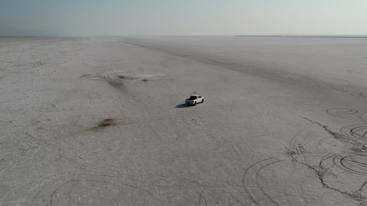 Drone Follows White Pickup Truck Driving Slowly Over Bonneville Salt Flats Sunset