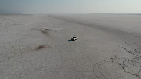 Drone Follows White Pickup Truck Driving Slowly Over Bonneville Salt Flats Sunset