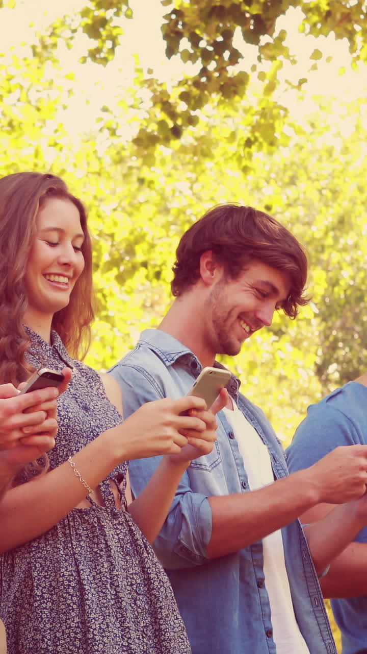 un joven guapo leyendo un libro apoyado en un árbol.