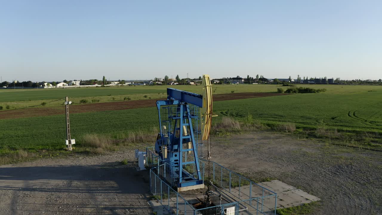 антенна: масляный насос на закате в сельской местности, старый стальной шкив, извлекающий масло