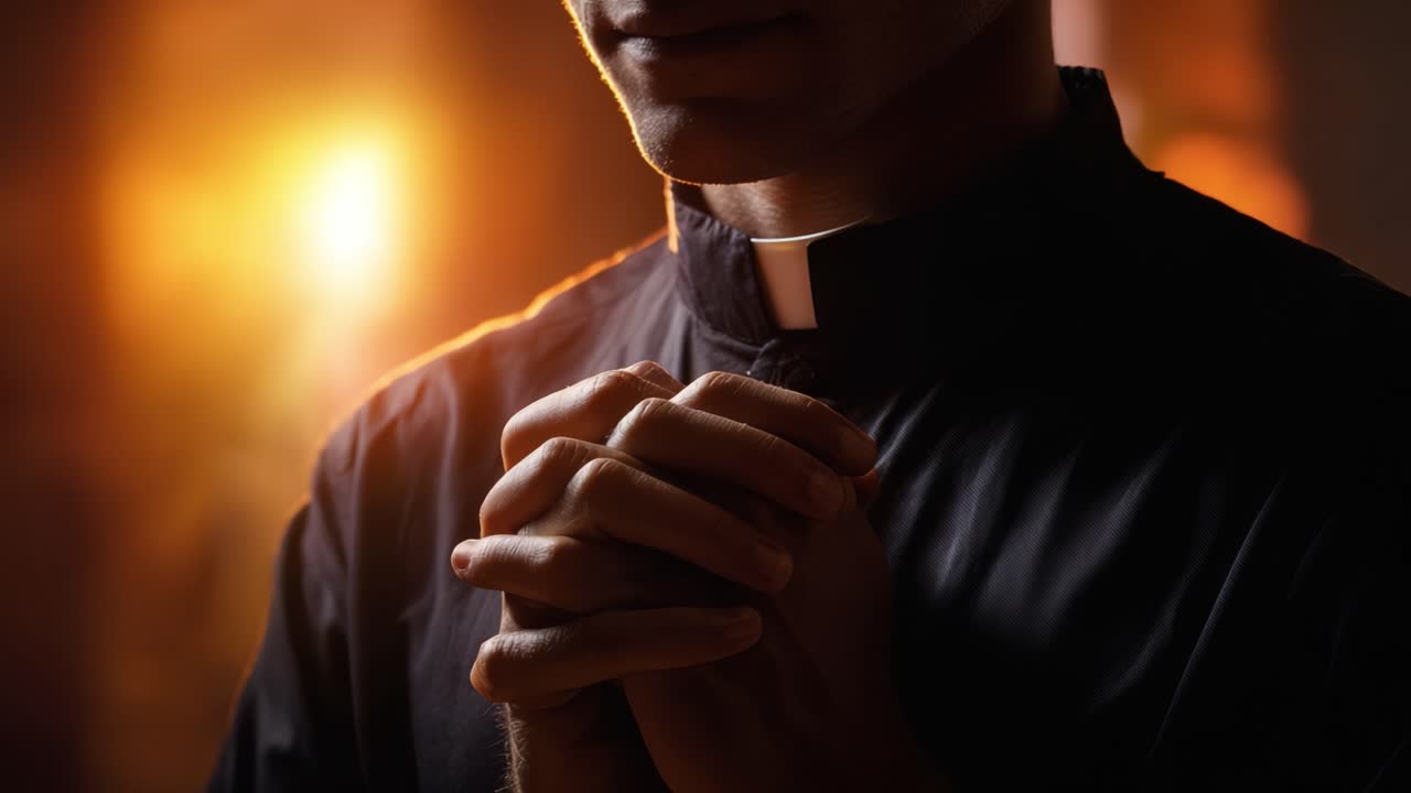 Una persona in una scura camicia clericale con le mani giunte in preghiera, illuminata da una luce calda, che incarna riflessione, fede e spiritualità in un'atmosfera serena