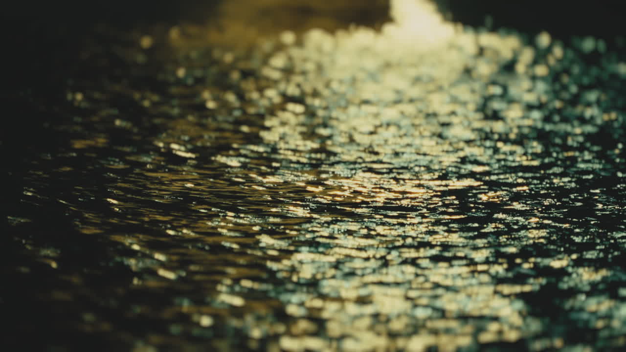 Acqua increspata e scintillante al crepuscolo. Scatto sfocato.