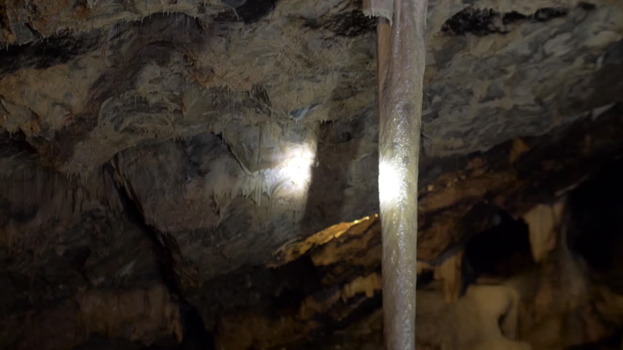 un gran estalagnato en una cueva de estalactita está iluminado por una linterna