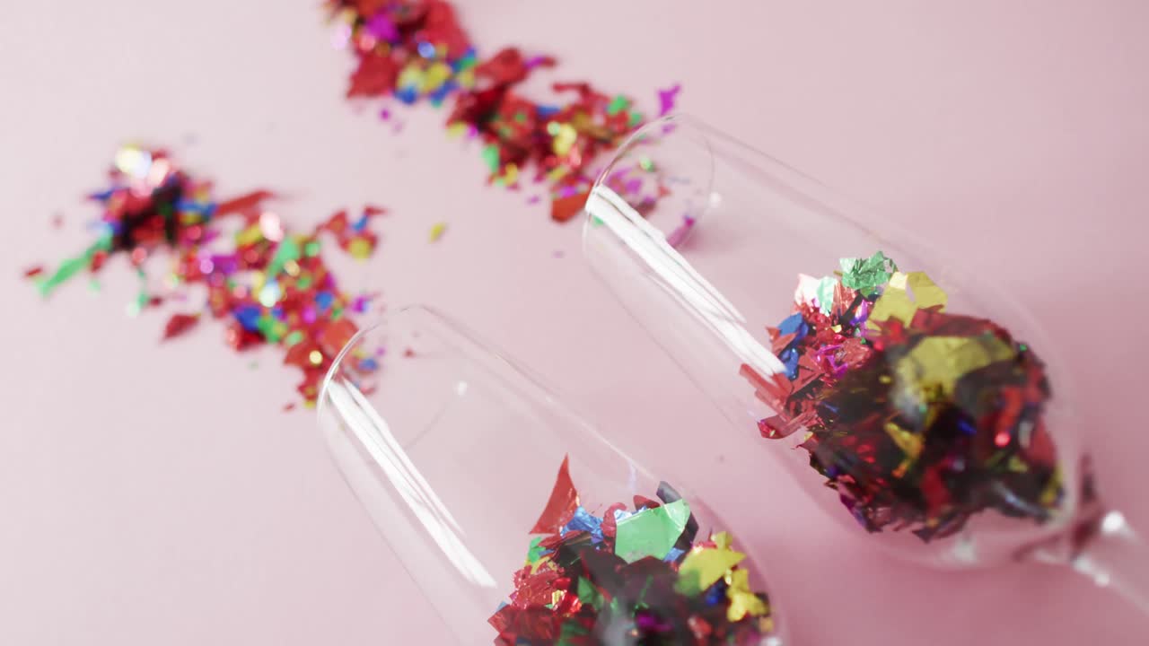 Champagne glasses with confetti on pink background at new year's eve