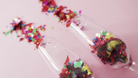 Champagne glasses with confetti on pink background at new year&#039;s eve