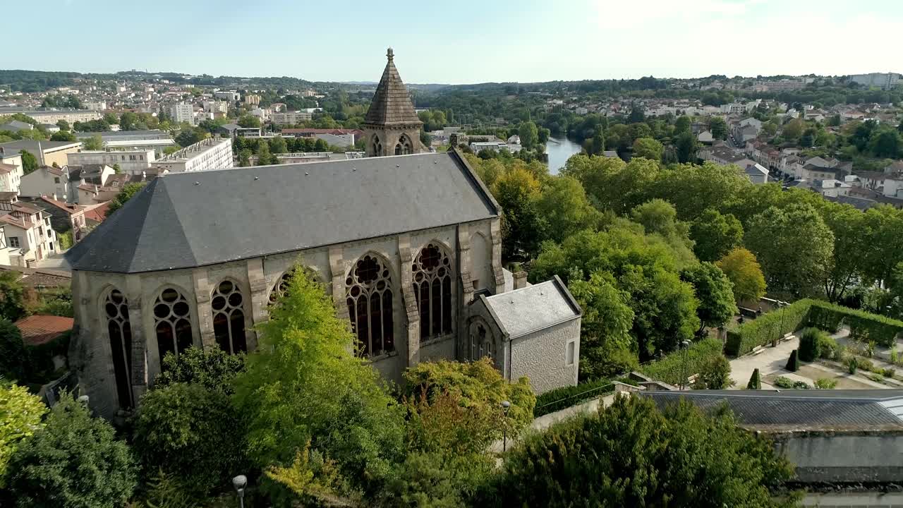 Botanischer Garten Limoges und historische Kapelle, umgeben von Pflanzenreihen und Grünflächen. Die Stadtlandschaft und Wohngebäude sind im Hintergrund sichtbar. Luftaufnahme aus großer Höhe.