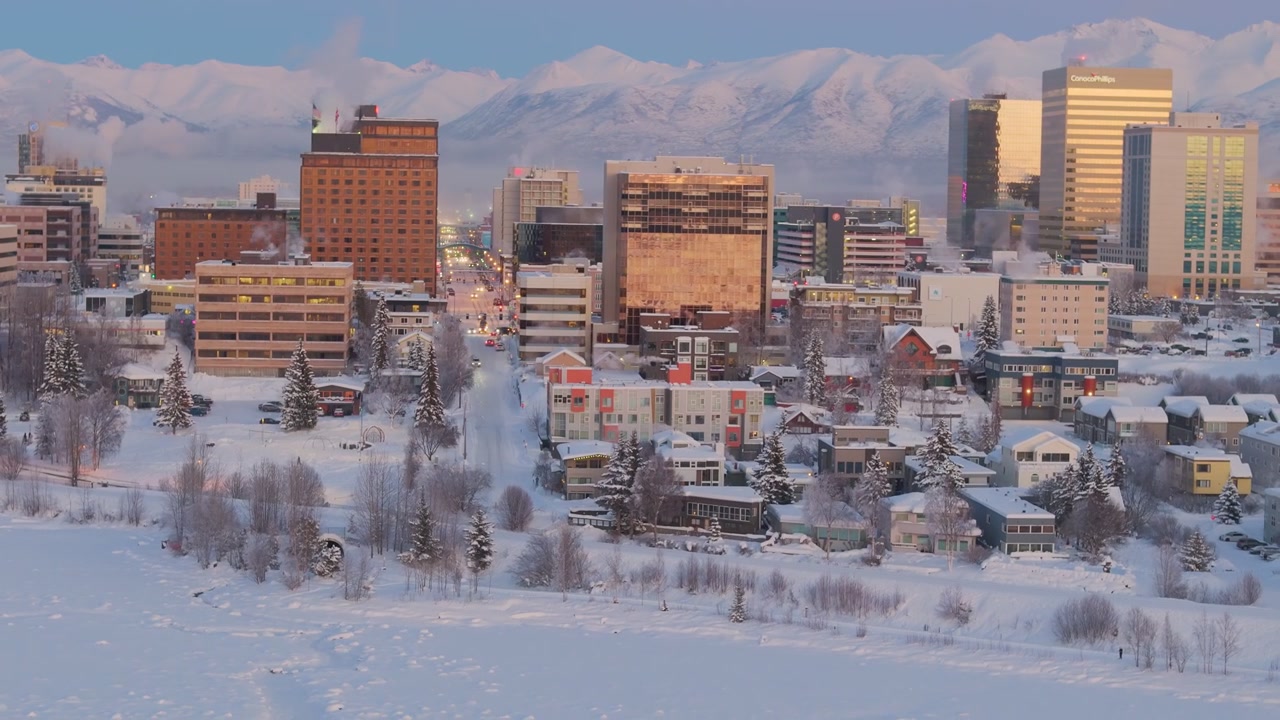 Anchorage, Alaska, kaupungin keskustan siluetti talvella hämärässä vuorten kanssa taustalla, ilmakuvana yleiskuva.