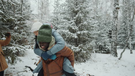 friends doing piggyback ride in winter forest