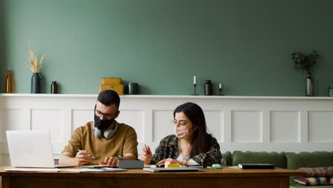 Vista-De-Miedo-De-Un-Estudiante-Con-Auriculares-Hablando-Con-Una-Compañera-En-La-Mesa-Discutiendo-Sobre-Un-Proyecto-Usando-Una-Computadora-Portátil