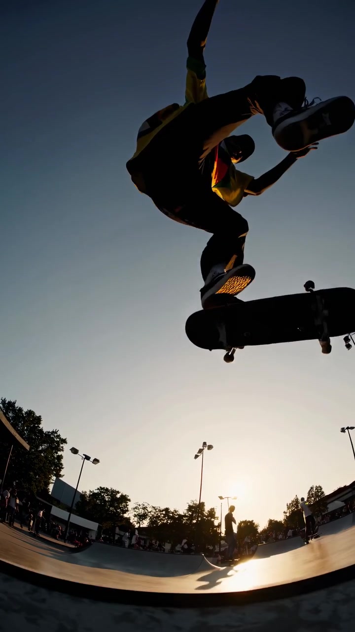 Skateboarder udfører et Ollie-trick i en skatepark ved solnedgang