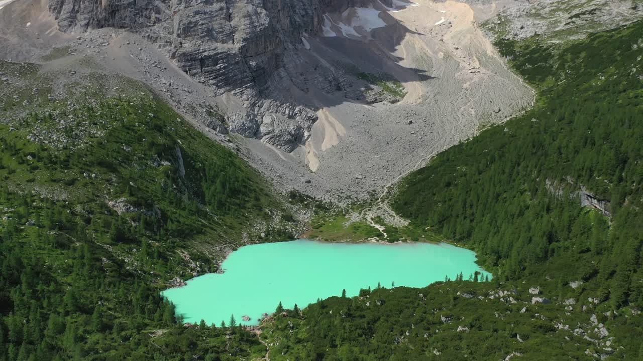 Lake Sorapis bright turqoise water in the Dolomites Italy, pull back aerial