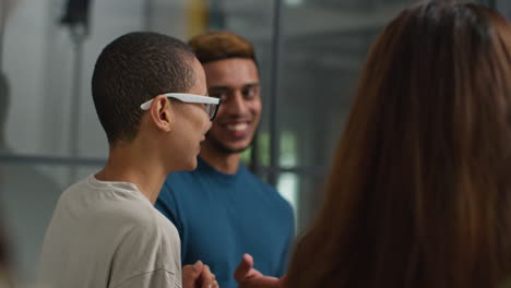 a group of diverse young professionals laughing and talking during a casual meeting at the office