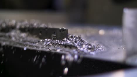 close up of metal filings fall from a vibrating ramp into a large cardboard box