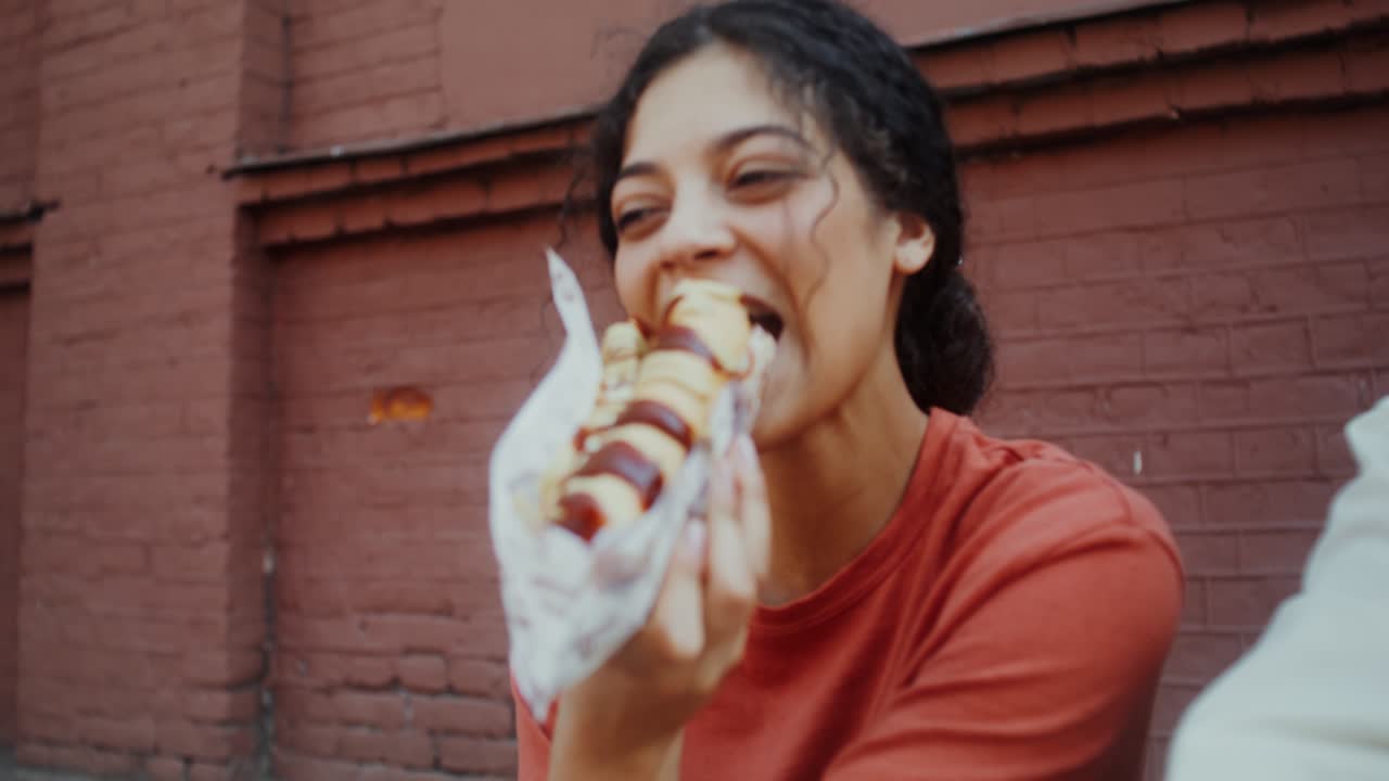 mujer comiendo un perrito caliente al aire libre