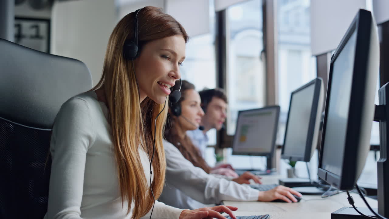 Support service agent talking in call center. Positive woman typing computer