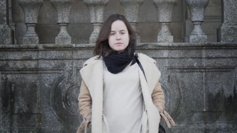 Young-female-tourist-in-warm-clothing-walking-down-steps-in-front-of-historical-building,-slow-motion