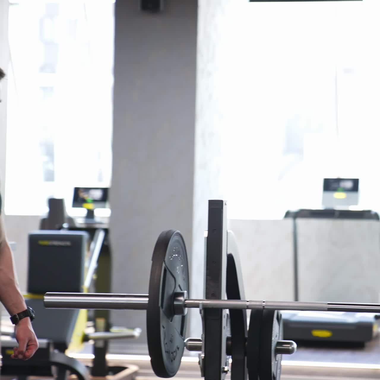 Man training in the gym. Muscular man putting heavy plates on barbell and lifting in gym