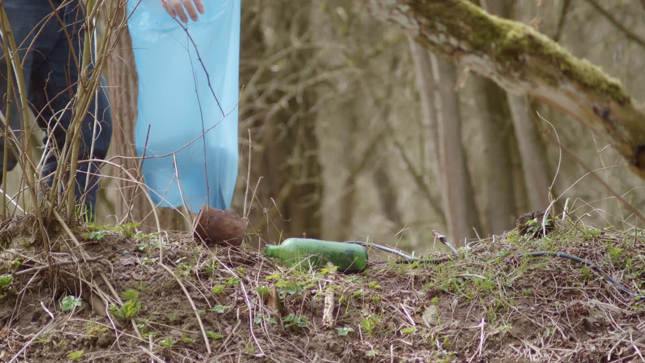 자원 봉사자는 나무 산책로를 따라 쓰레기를 모으고 쓰레기 봉투에 넣습니다.