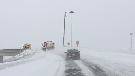 driving on a freeway and over an overpass behind plow trucks on a winters day