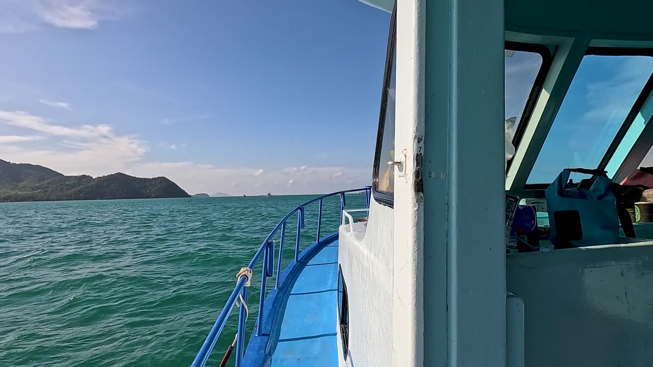 A boat glides through Phuket's turquoise waters, offering stunning views of distant islands under clear skies