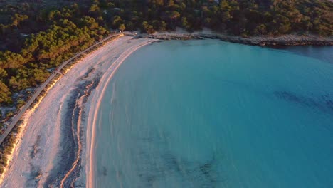 Son-Saura-beach-in-Menorca-Spain-at-sunset-with-golden-glow-on-the-white-sand