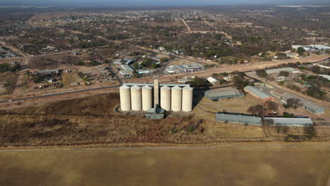 static high angle drone view of cylindrical silos in drought stricken landscape