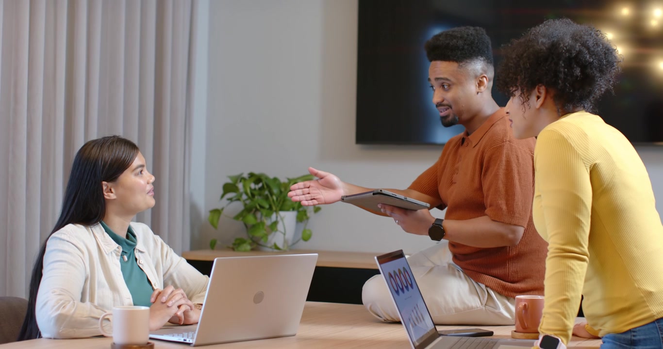 African American coworkers at meeting table, presenter tapping tablet, gesturing and seeking input