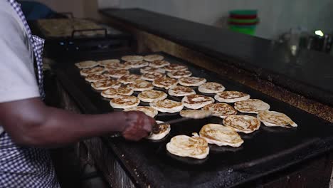 close-up of a man cooking parottas in a hot griddle. slow motion of flipping the hot parottas.