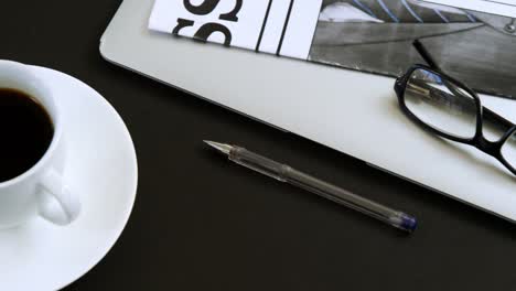 laptop, spectacles, newspaper, coffee and pen on black background 4k