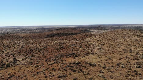 un plano general extremo que captura el paisaje de terreno arbustivo contra un cielo azul claro