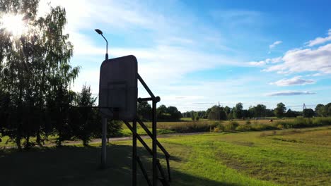 Vintage-looking-basketball-board-silhouette-in-small-village,-descend-view