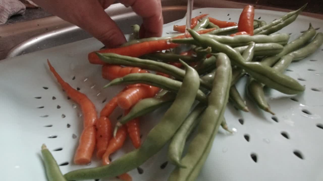 흐르는 물 아래 싱크대에서 직접 재배한 유기농 채소를 손으로 씻는 남성