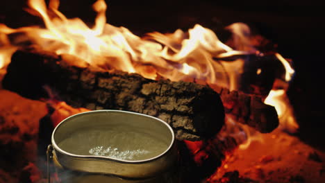 the camp kettle is boiling around the fire preparation of hot tea and food on a hike 4k video